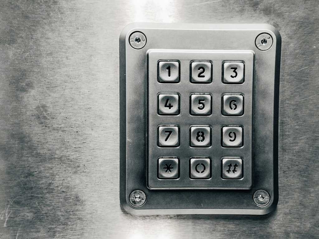 A silver metal numeric pad set into a steel wall.