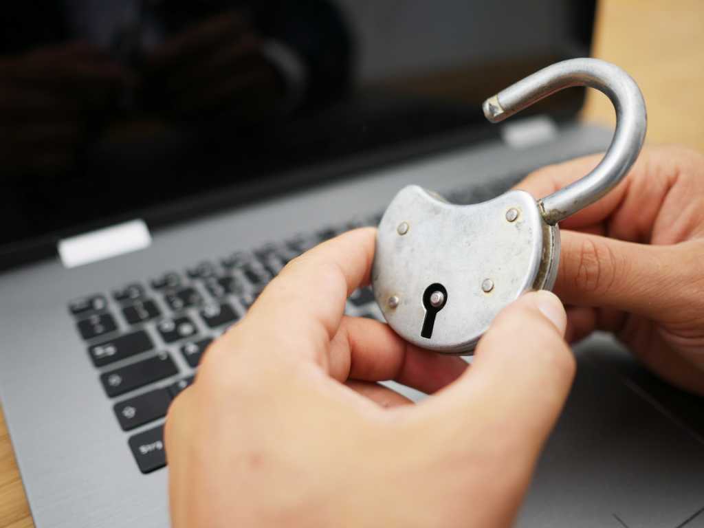 Hands holding a metal lock in front of a laptop