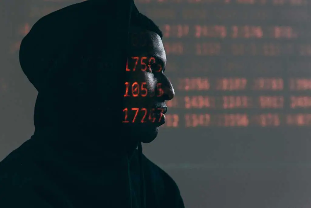 Hacker in a dark room with LED numbers lit on their skin