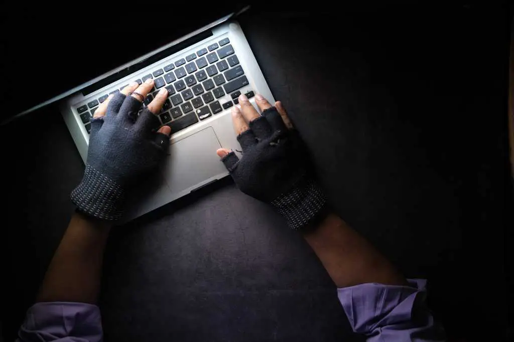 hacker hands stealing data from laptop top down