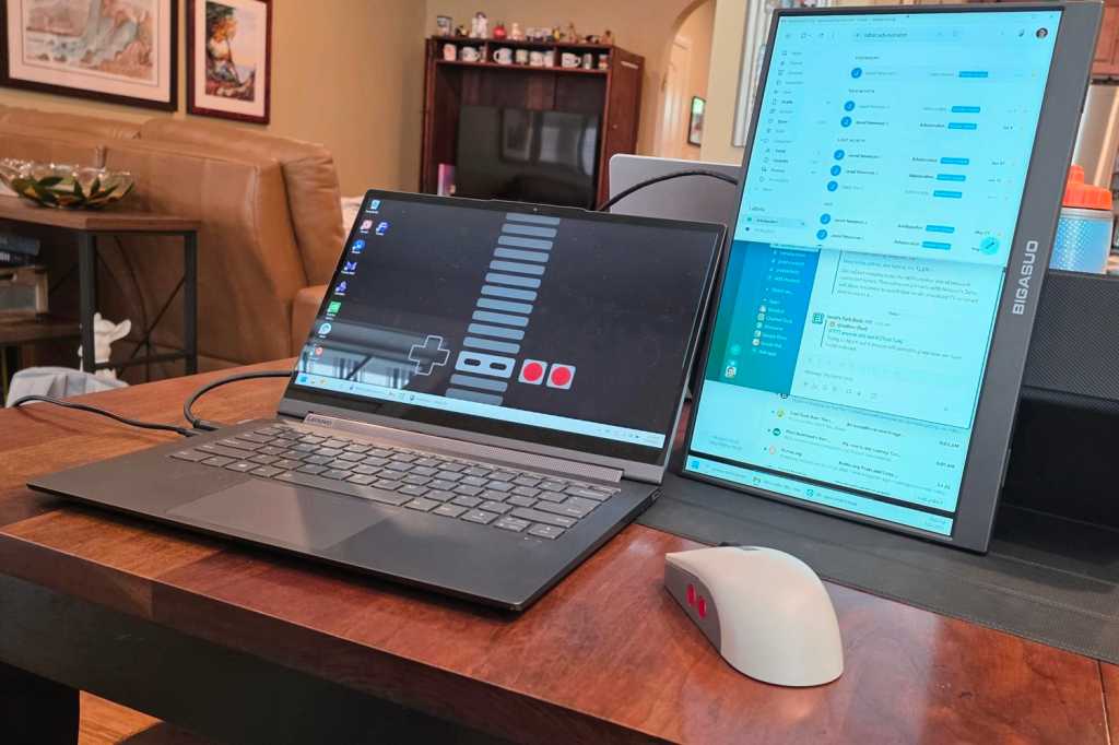 Portable monitor stood up vertically next to a laptop on a dining room table.