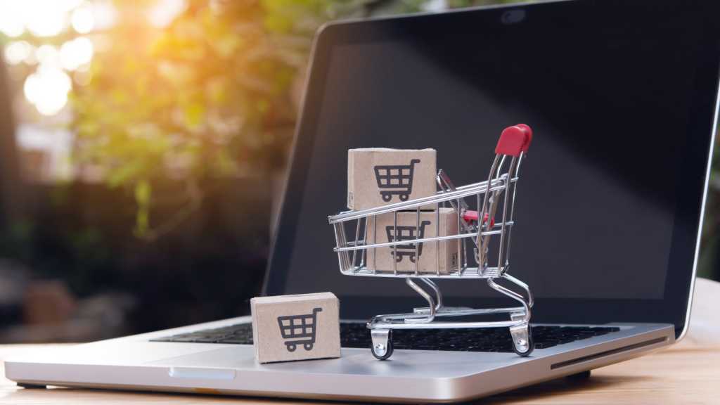 Mini shopping cart with model packages on a laptop