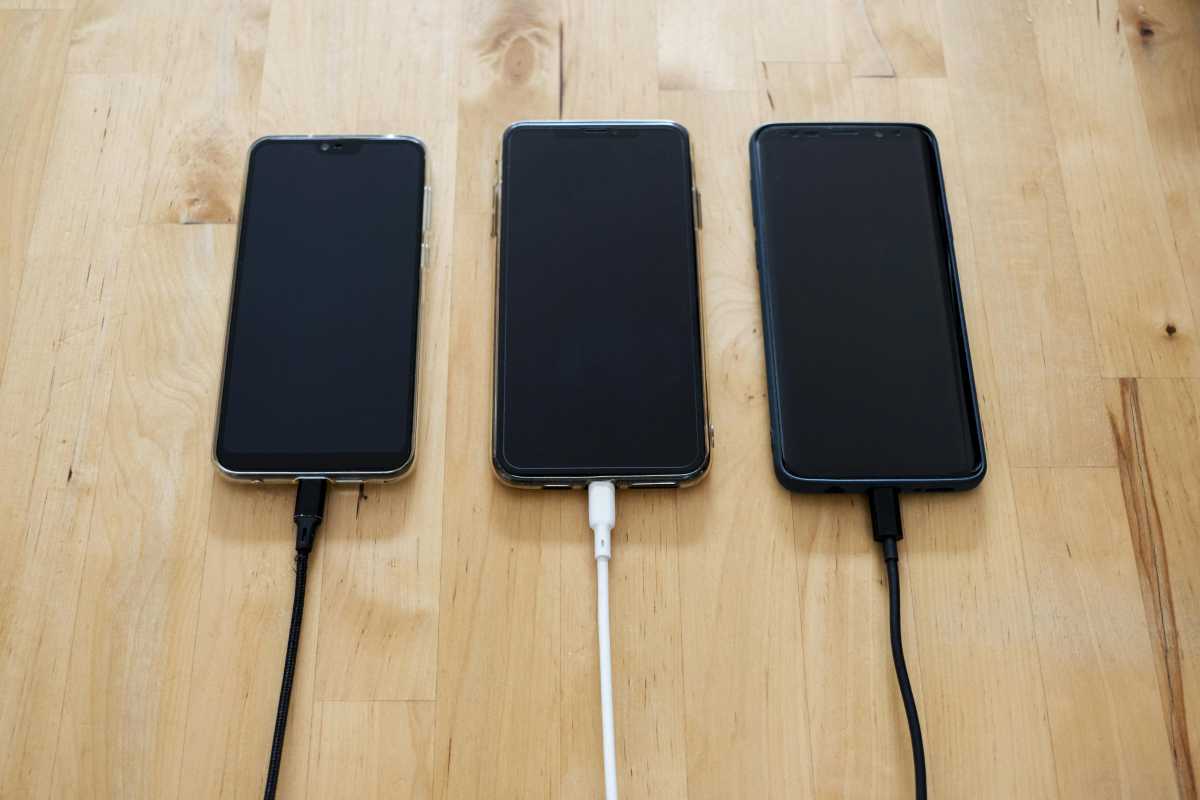 Trois téléphones mobiles avec des fils de charge, côte à côte