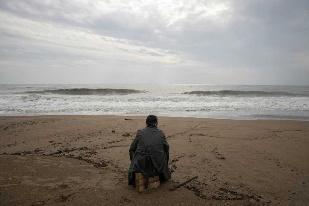 Lone traveler sitting on luggage on a beach
