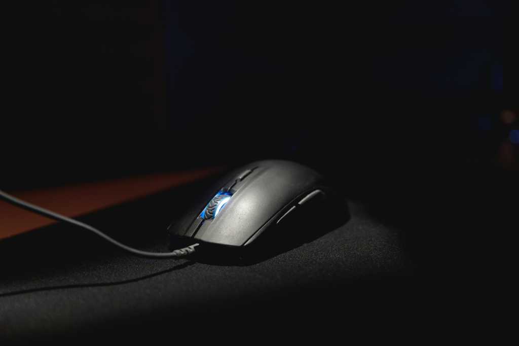 A computer mouse lit dramatically on a black mouse mat
