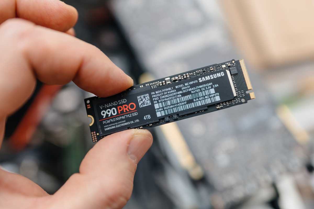 Homme tenant un SSD Samsung 990 PRO entre les doigts sur un héros d'ordinateur portable exposé