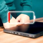 Laptop on wooden desk with empty battery icon indicator