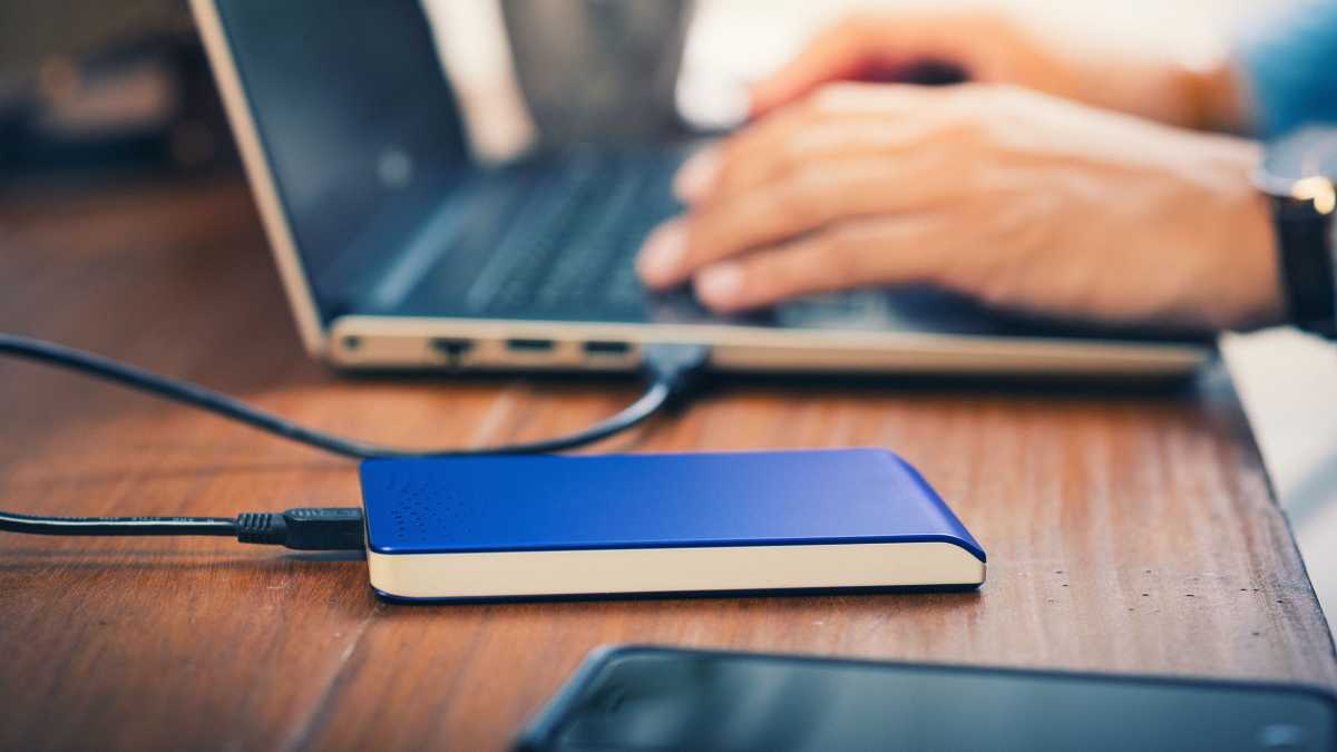 SSD/HDD externe sur une table à côté d'un ordinateur portable/ordinateur portable, homme tapant sur le clavier