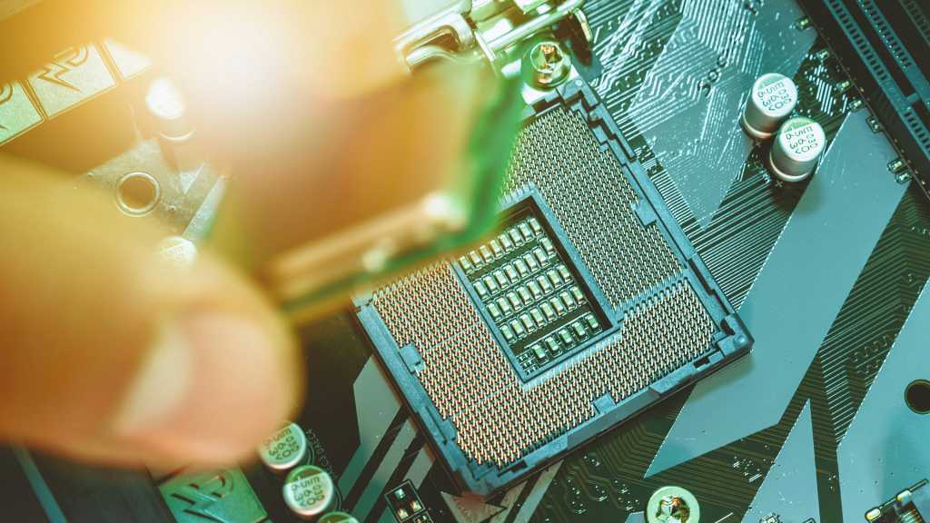 Fingers placing CPU processor chip into motherboard socket