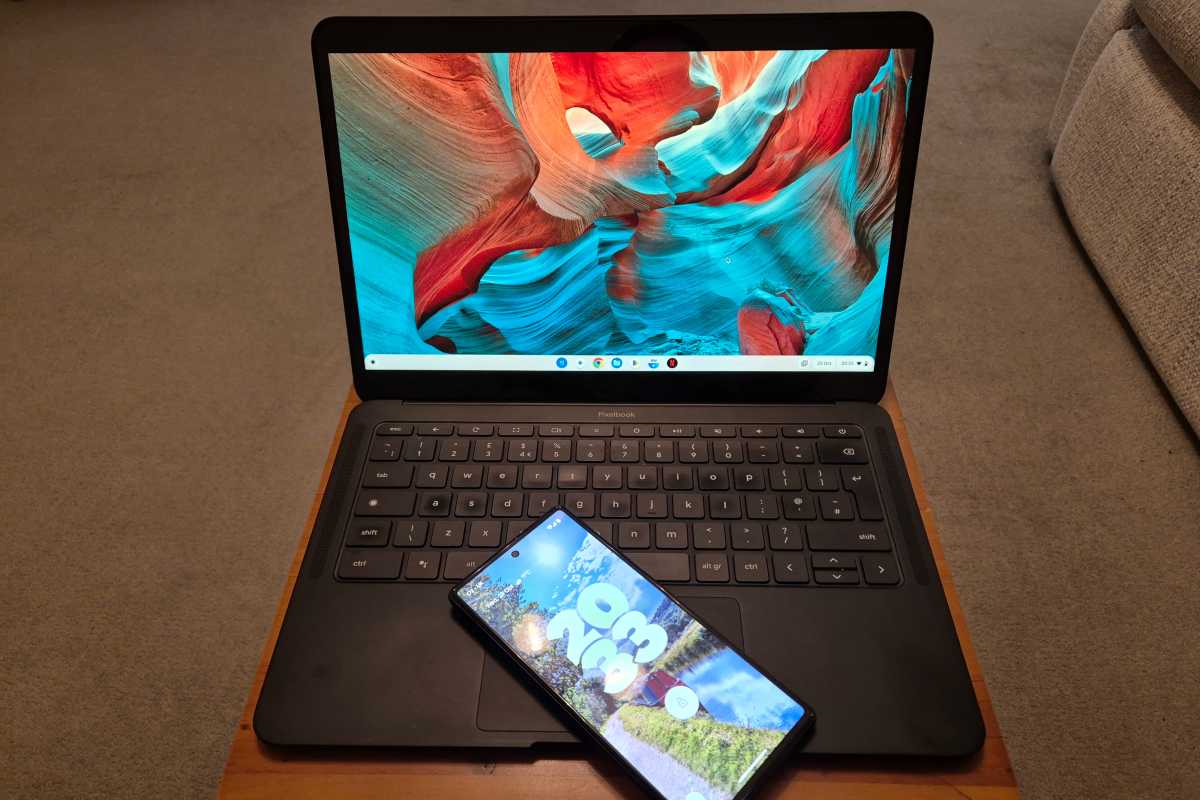Ordinateur portable Chromebook sur un bureau à plateau en bois avec téléphone Android sur clavier