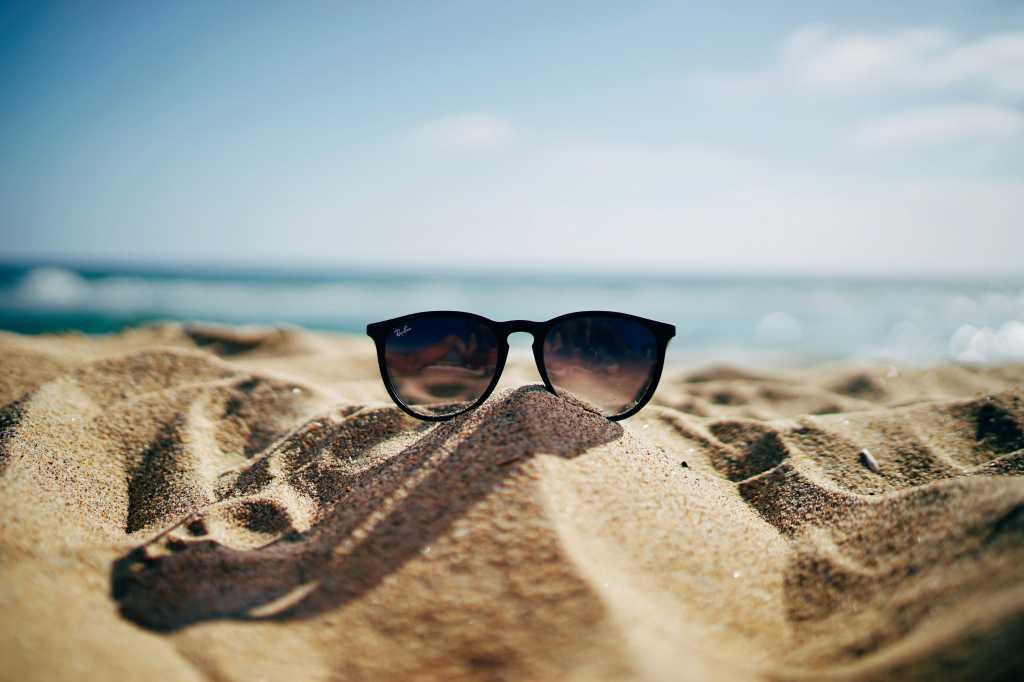 Sunglasses on top of a sand on a beach