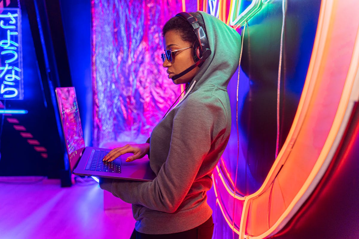A tech-savvy individual using a laptop in a neon-lit room, symbolizing cybersecurity.