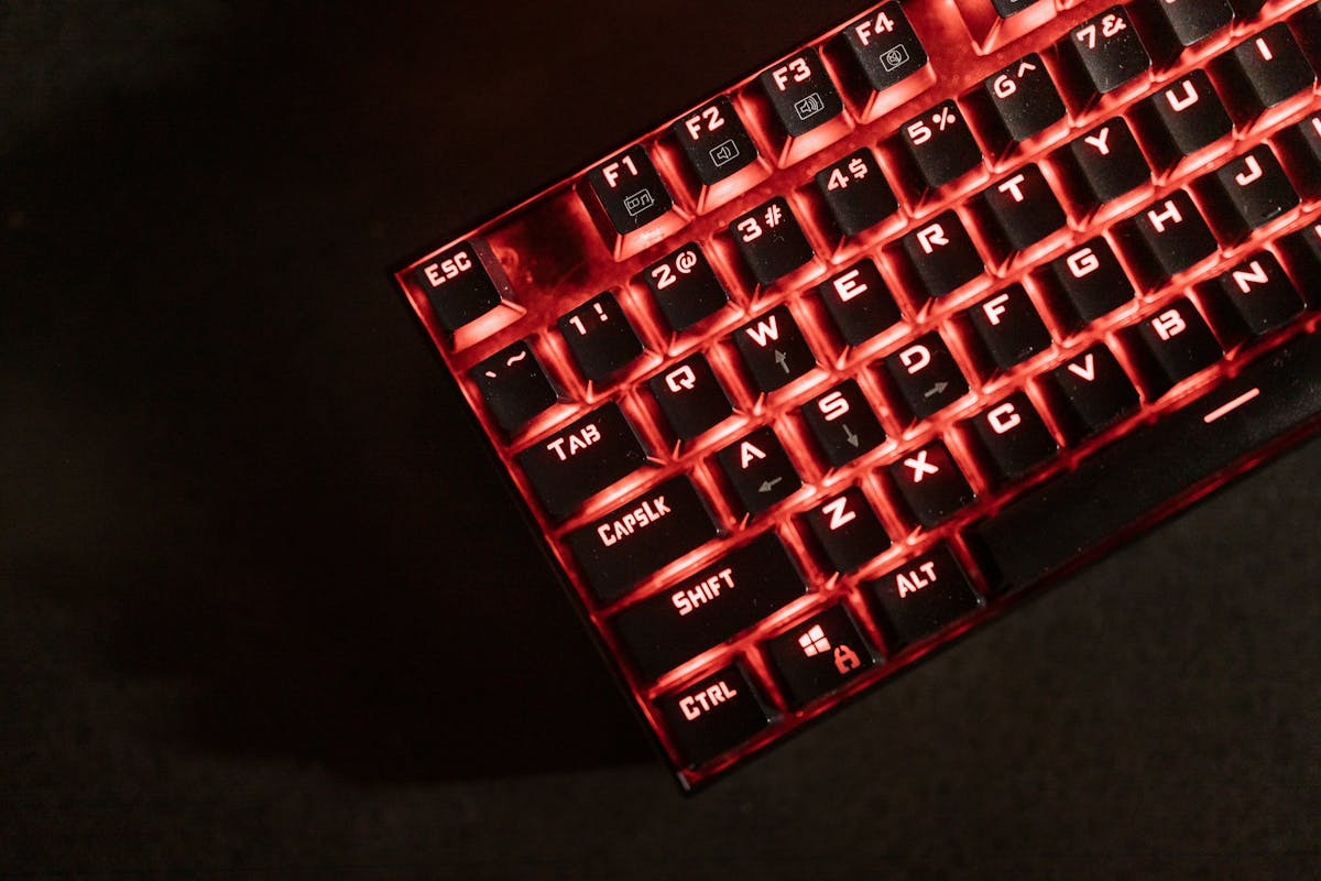 Close-up view of a red illuminated mechanical gaming keyboard in a dark room.