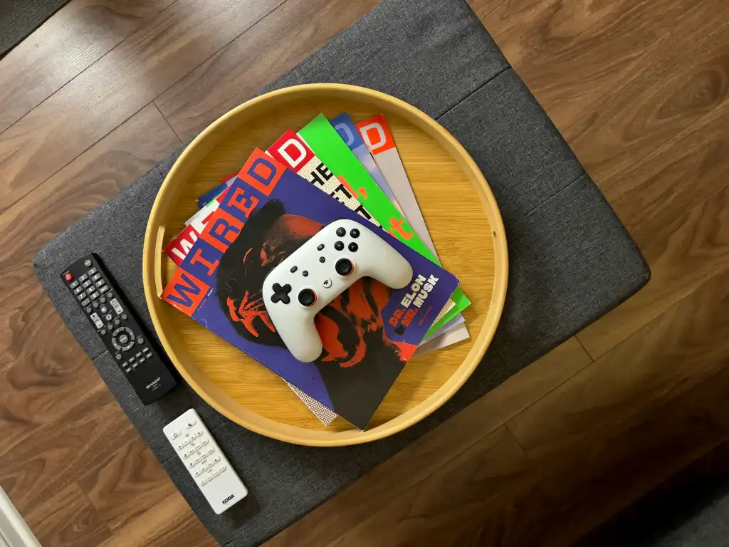 Wired magazines in a wood tray on a coffee table, with a controller on top of the stack