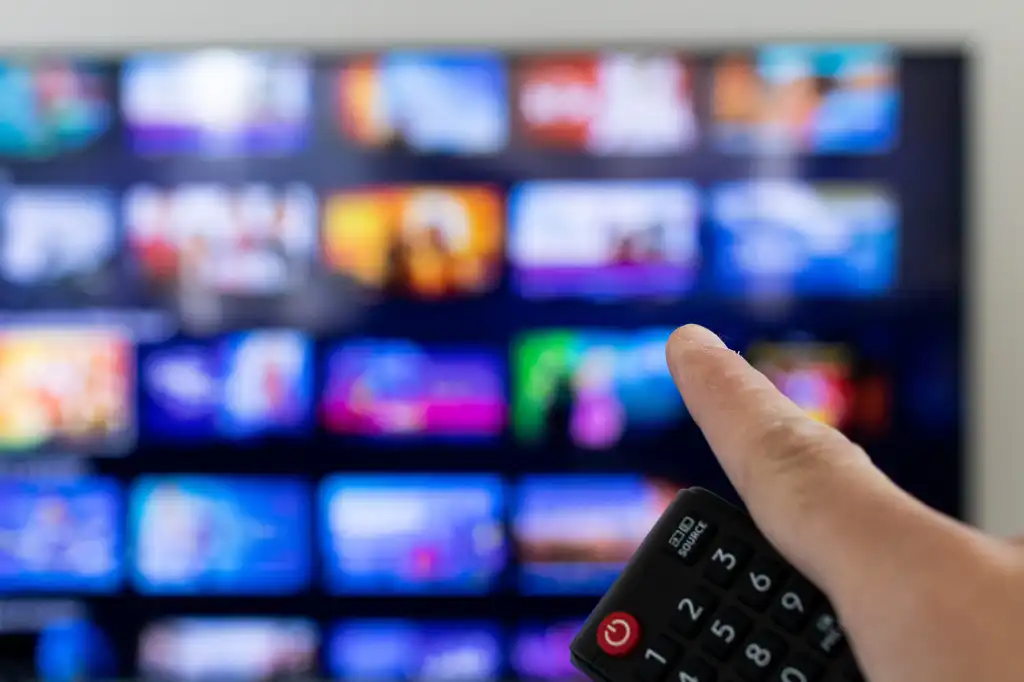 Man holding remote and pointing at smart TV with streaming options