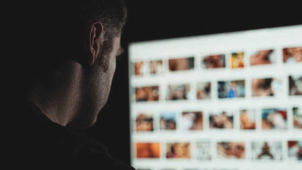 Mann schaut Pornos am PC