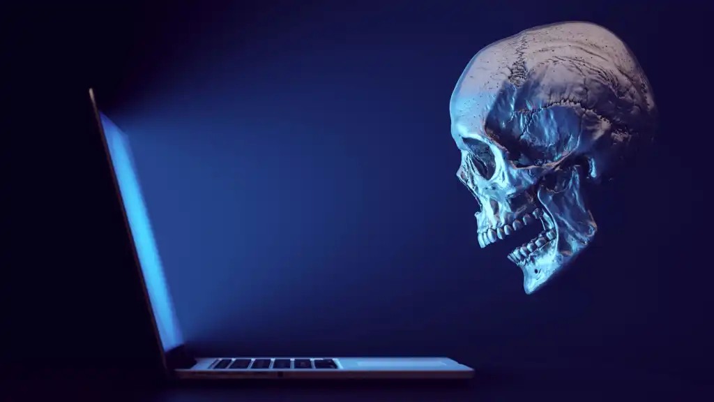 Totenkopf als Symbol für Hacker blickt ratlos auf Laptop-Bildschirm