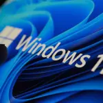 Finger touching Windows 11 logo on screen in dark room