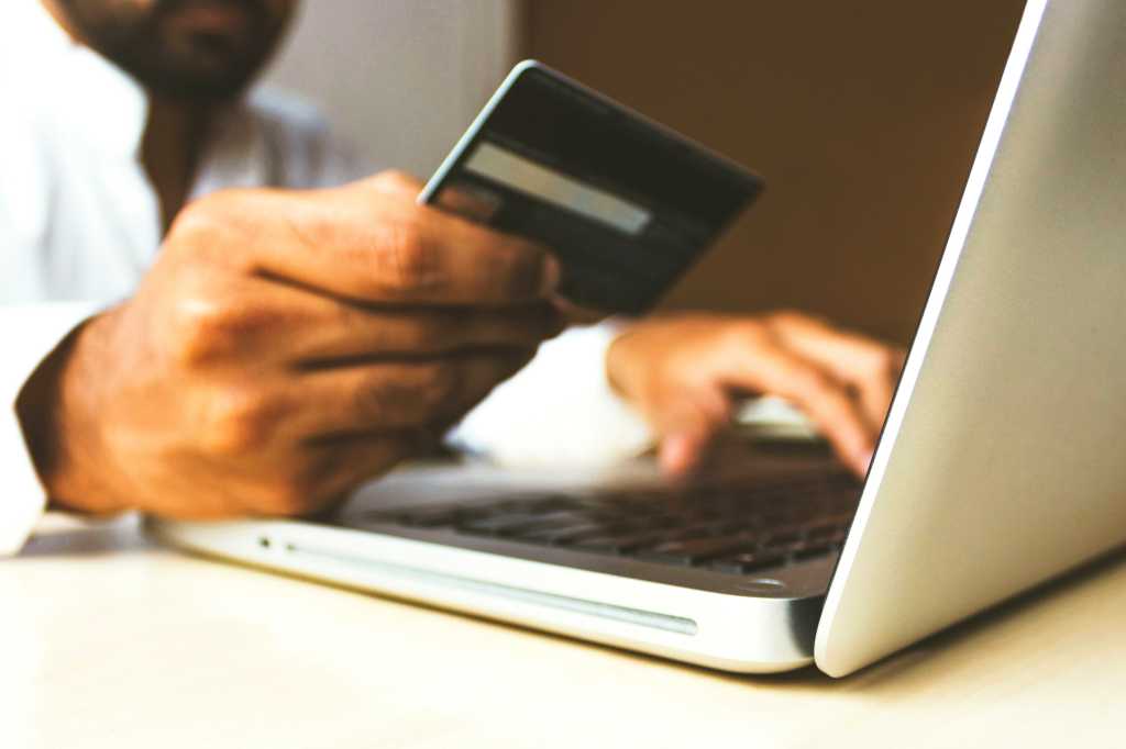 Man on laptop holding credit card making online purchase