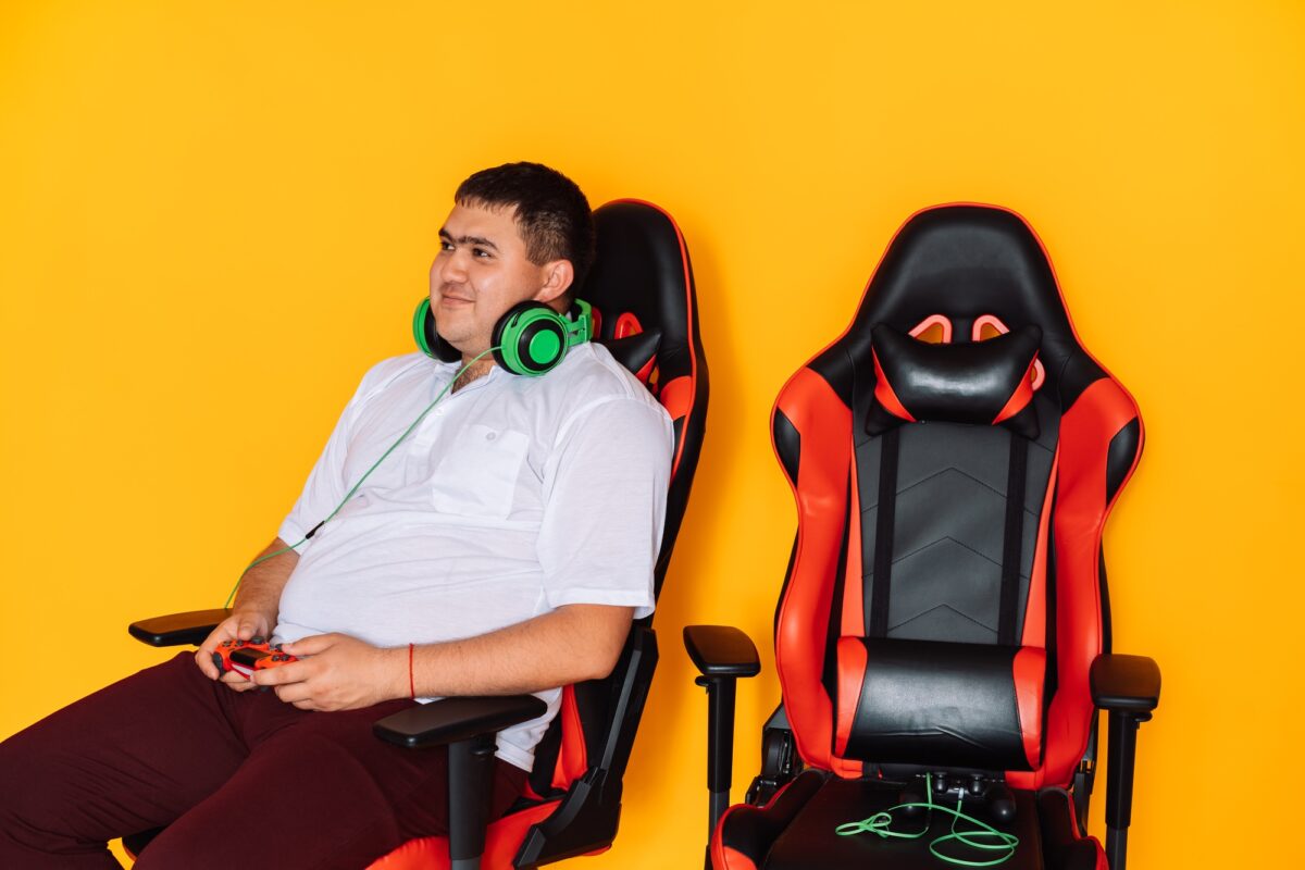 Guy holding game controller playing video games while sitting on gaming chair