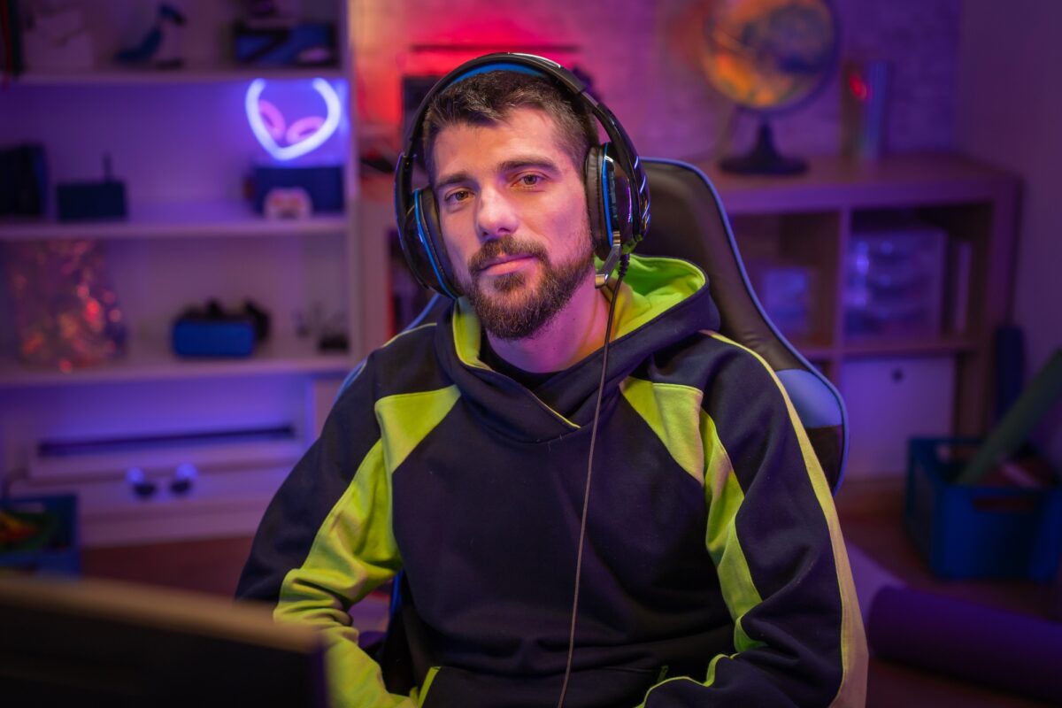 Portrait d'un joueur regardant la caméra avec des lumières néon colorées.